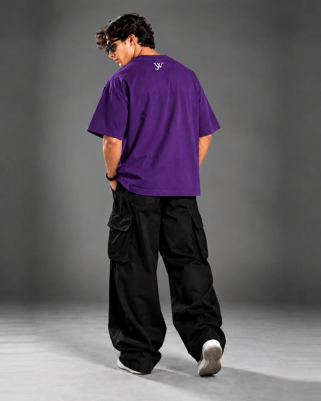 Studio portrait of model wearing the Royal Purple T-Shirt, back view with YW monogram print, over-the-shoulder pose