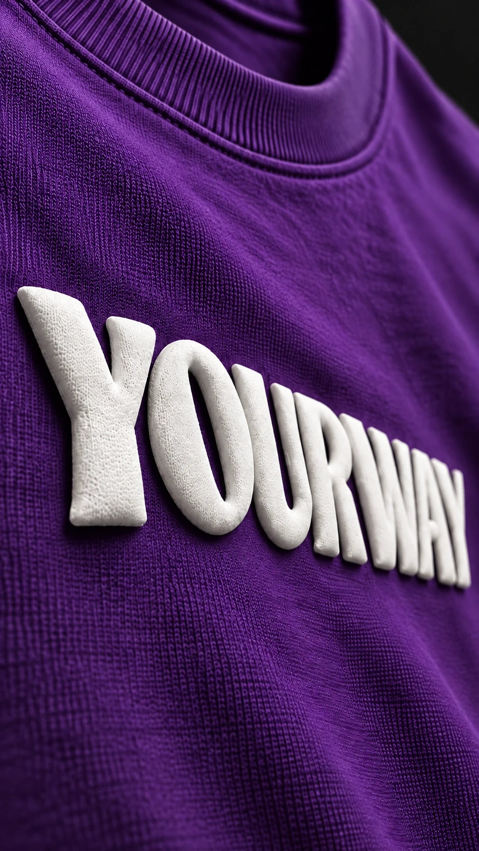 Close-up of the raised white YOURWAY puff print wordmark on the Royal Purple T-Shirt fabric