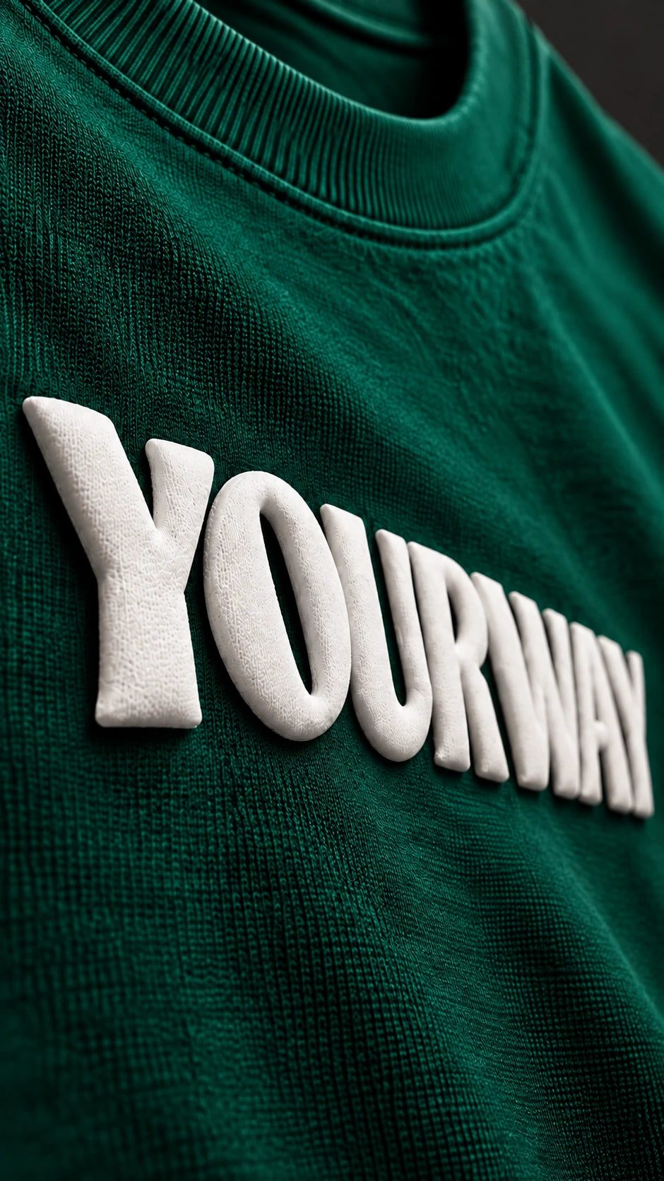 Close-up of the raised white YOURWAY puff print wordmark on the Emerald Green T-Shirt fabric